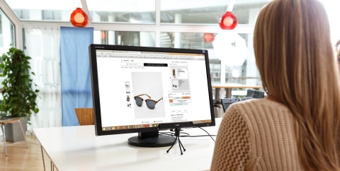 A woman looking at an e-commerce website on a laptop screen with Tobii Pro X2 eye tracker in front of the screen mounted on tripod.