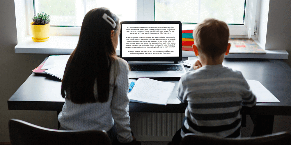 2 children reading on a laptop