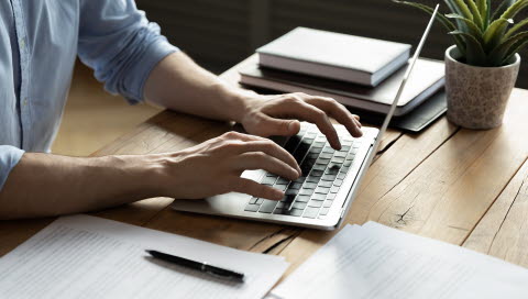 man typing on a laptop keyboard