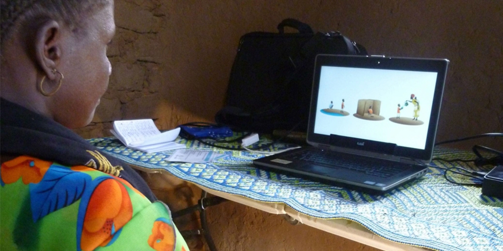 A woman performs an eye tracking test with Tobii Pro X2-60 in a traditional mud brick home.